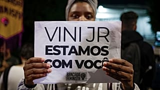A woman holds a sign with a message that reads in Portuguese; "Vini, we are with you," during a protest against the racism suffered by Brazilian soccer star Vinicius Junior.