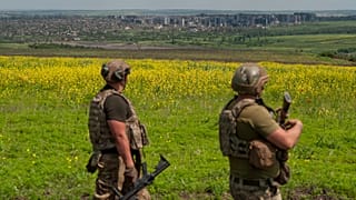 Zwei ukrainische Soldaten mit der Stadt Bachmut im Hintergrund
