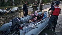 Rescue workers attempt to tow boats carrying residents being evacuated from a flooded neighborhood in Kherson, Ukraine, Tuesday, June 6, 2023. 
