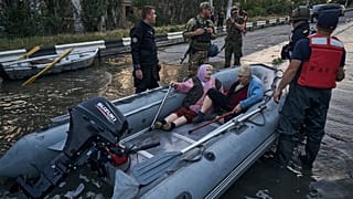 Rescue workers attempt to tow boats carrying residents being evacuated from a flooded neighborhood in Kherson, Ukraine, Tuesday, June 6, 2023.