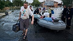 Rescue workers attempt to tow boats carrying residents being evacuated from a flooded neighborhood in Kherson, Ukraine, Tuesday, June 6, 2023. 
