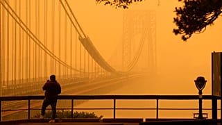 A Man talks on his phone as he looks through the haze at the George Washington Bridge in New Jersey 