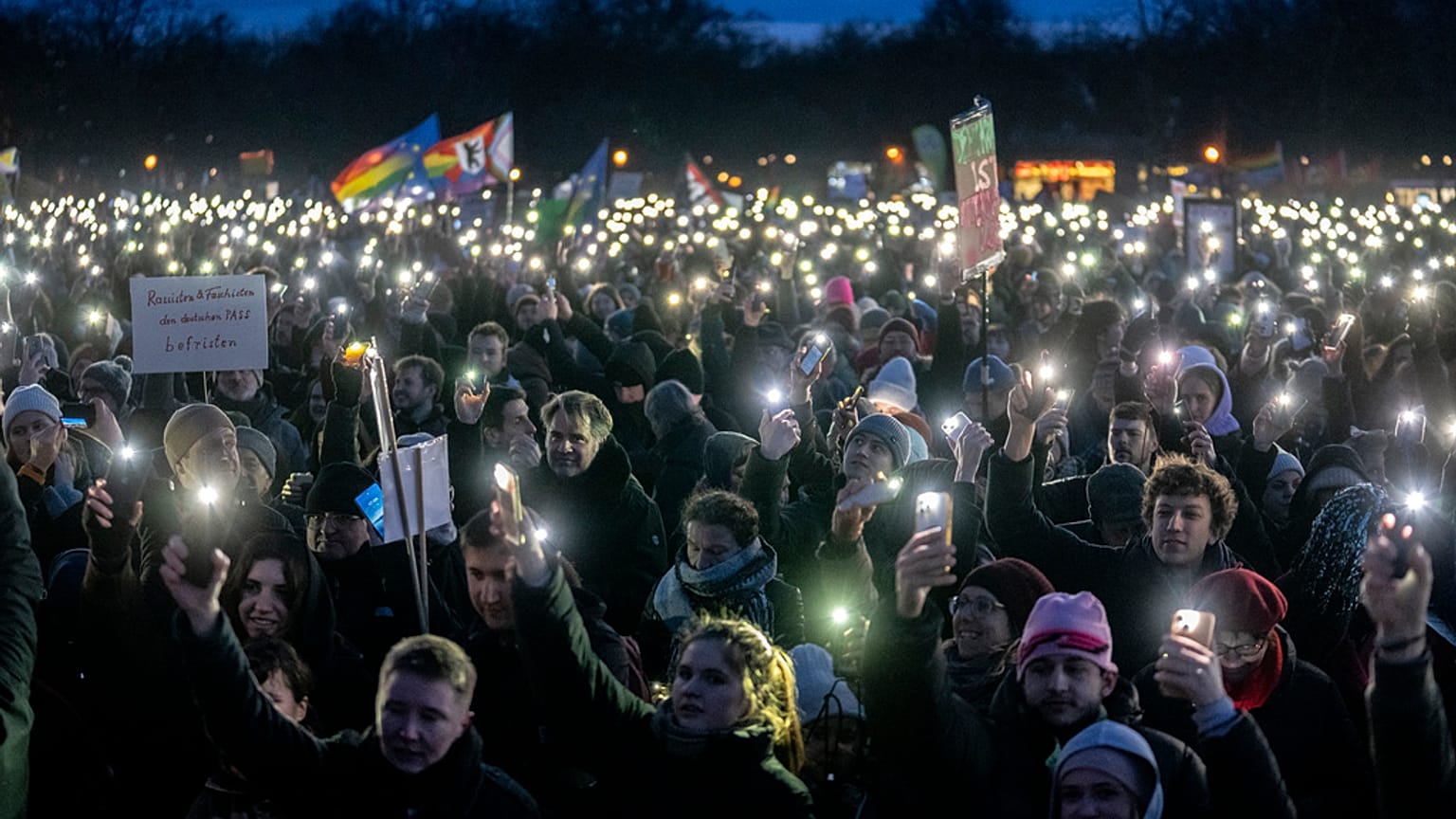 People hold up their cell phones as they protest against the AfD party and right-wing extremism in front of the Reichstag building in Berlin, Germany, Sunday, Jan. 21, 2024. 