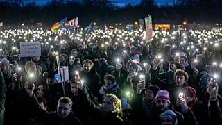People hold up their cell phones as they protest against the AfD party and right-wing extremism in front of the Reichstag building in Berlin, Germany, Sunday, Jan. 21, 2024.