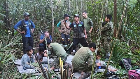 In this photo released by Colombia's Armed Forces Press Office, soldiers and Indigenous men tend to the four Indigenous brothers who were missing after a deadly plane crash.