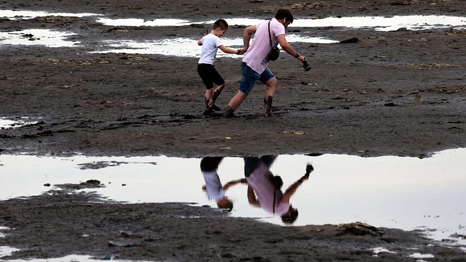 Des habitants de Zaporijjia marchent dans une vase, conséquence du retrait de l'eau du Dniepr après la destruction du barrage de Kakhovka, 