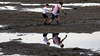 Des habitants de Zaporijjia marchent dans une vase, conséquence du retrait de l'eau du Dniepr après la destruction du barrage de Kakhovka, 