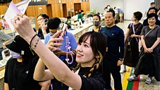 A Japanese fan takes a photo of stationary as she queues up to buy a special commemorative stamp series of K-pop megastars BTS,