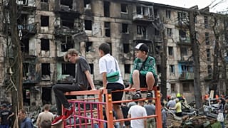 Children look at the scene of the latest Russian rocket attack that damaged a multi-storey apartment building in Kryvyi Rih, Ukraine, Tuesday, June 13, 2023.