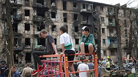Children look at the scene of the latest Russian rocket attack that damaged a multi-storey apartment building in Kryvyi Rih, Ukraine, Tuesday, June 13, 2023.