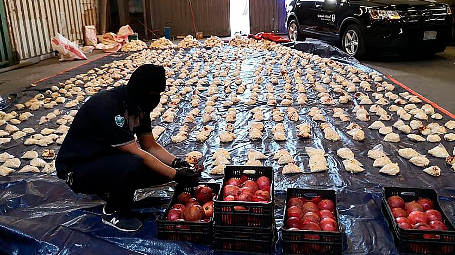 Um funcionário da alfândega saudita abre romãs importadas usadas para tentar contrabandear mais de 5 milhões de comprimidos de Captagon, em 2021.