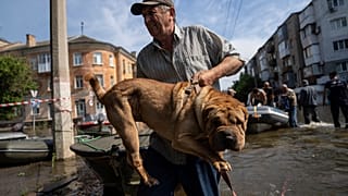 FILE - A man carries his dog after evacuation from a flooded neighborhood of the left bank Dnipro river, in Kherson, Ukraine, Friday, June 9, 2023.