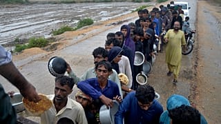 People wait for their turn to receive free food distributed by volunteers outside a camp as Cyclone Biparjoy was approaching.
