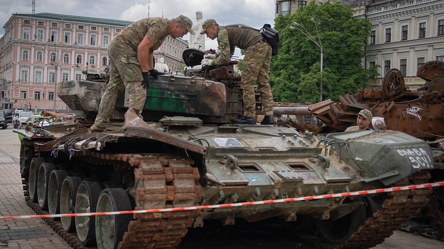 Sappers inspect a damaged Russian tank installed as a symbol of war in central Kyiv
