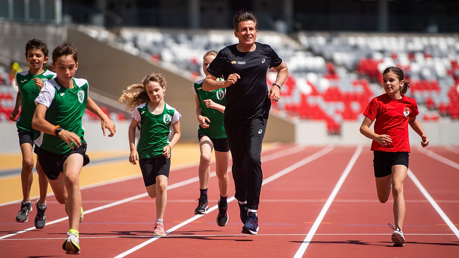A WA elnöke, Sebastian Coe (középen) gyerekekkel fut a budapesti atlétikai világbajnokság futópályáján a Nemzeti Atlétikai Központban 2023.06.15-én. 