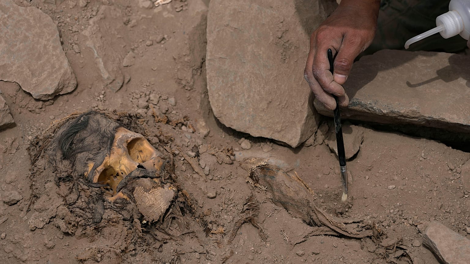 An archaeologist excavates a pre-Hispanic mummy that was discovered next to a training field in the El Rimac neighborhood of Lima, Peru, Thursday, June 15, 2023.