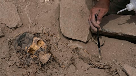 An archaeologist excavates a pre-Hispanic mummy that was discovered next to a training field in the El Rimac neighborhood of Lima, Peru, Thursday, June 15, 2023.