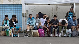 Διασωθέντες του ναυαγίου ανοιχτά της Πύλου περιμένουν να επιβιβαστούν σε λεωφορεία και να μεταβούν στο κέντρο υποδοχής μεταναστών στην Μαλακάσα