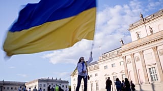 A woman waves a Ukrainian flag as she attends a protest against the war in Ukraine held in Berlin.