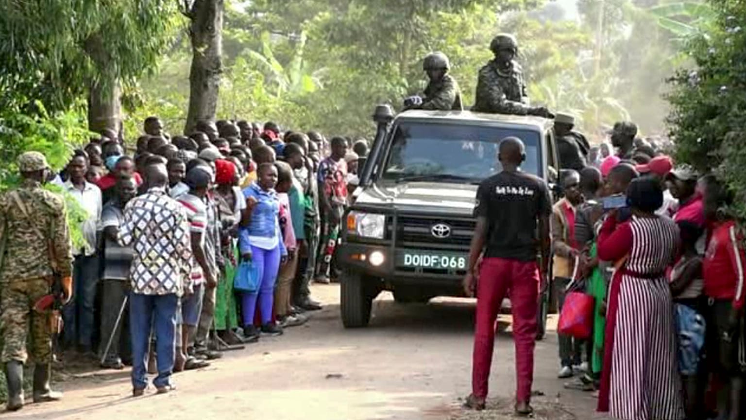 Security forces drive past a crowd of people gathered outside the Lhubiriha Secondary School following an attack in Mpondwe, Uganda, Saturday, June 17, 2023