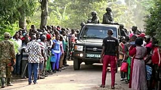 Security forces drive past a crowd of people gathered outside the Lhubiriha Secondary School following an attack in Mpondwe, Uganda, Saturday, June 17, 2023