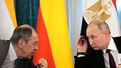 Vladimir Putin and Russian Foreign Minister Sergey Lavrov talk during a meeting with a delegation of African leaders and senior officials in St Petersburg