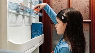 A child takes an egg from an empty fridge.