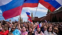 Thousands of people wave Russian national flags as they gather on Red Square to watch a concert dedicated to the Day of Russia in Moscow, Russia, Sunday, June 11, 2023.