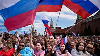 Thousands of people wave Russian national flags as they gather on Red Square to watch a concert dedicated to the Day of Russia in Moscow, Russia, Sunday, June 11, 2023.