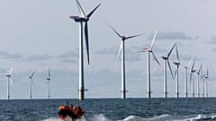 A speed boat passes by offshore windmills in the North Sea offshore from the village of Blavandshuk near Esbjerg, Denmark in this file photo