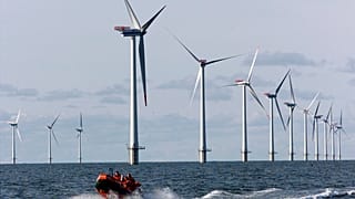 A speed boat passes by offshore windmills in the North Sea offshore from the village of Blavandshuk near Esbjerg, Denmark in this file photo