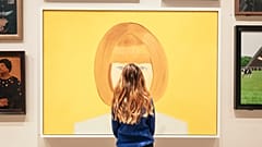 A woman stands in front of the National Portrait Gallery Collection
