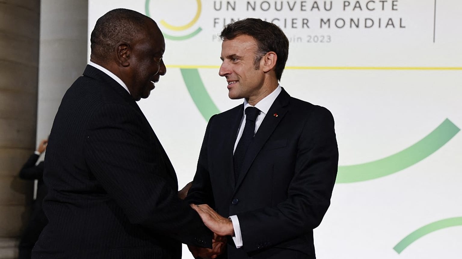 French President Emmanuel Macron (R) and South Africa's President Matamela Cyril Ramaphosa greet at the Palais Brogniart for the New Global Financial Pact Summit in Paris.