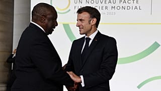 French President Emmanuel Macron (R) and South Africa's President Matamela Cyril Ramaphosa greet at the Palais Brogniart for the New Global Financial Pact Summit in Paris.