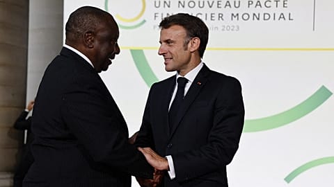 French President Emmanuel Macron (R) and South Africa's President Matamela Cyril Ramaphosa greet at the Palais Brogniart for the New Global Financial Pact Summit in Paris.
