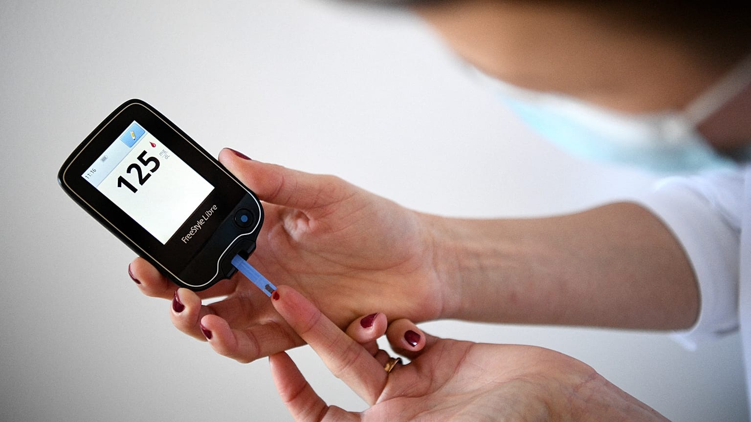 A woman with diabetes uses a glucometer to measure the glycemia in her blood in Paris on 24 March 2020.