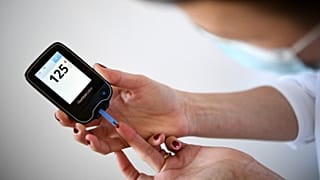A woman with diabetes uses a glucometer to measure the glycemia in her blood in Paris on 24 March 2020.