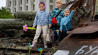 Kinder auf einem ausgebrannten russischen Panzer in Kiew, Ukraine, 11. Juni 2023.
