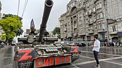 Militares sentados en un tanque con una bandera de la compañía paramilitar Wagner.