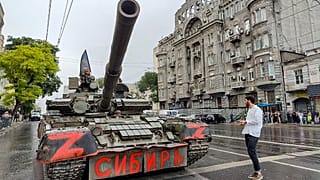 Militares sentados en un tanque con una bandera de la compañía paramilitar Wagner.
