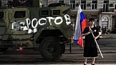 Homem segura bandeira russa em frente a viatura do grupo Wagner em Rostov