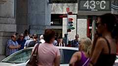 People walk near a sign indicating 43 degrees Celsius as near record temperatures hit Bilbao, Spain in 2022. 
