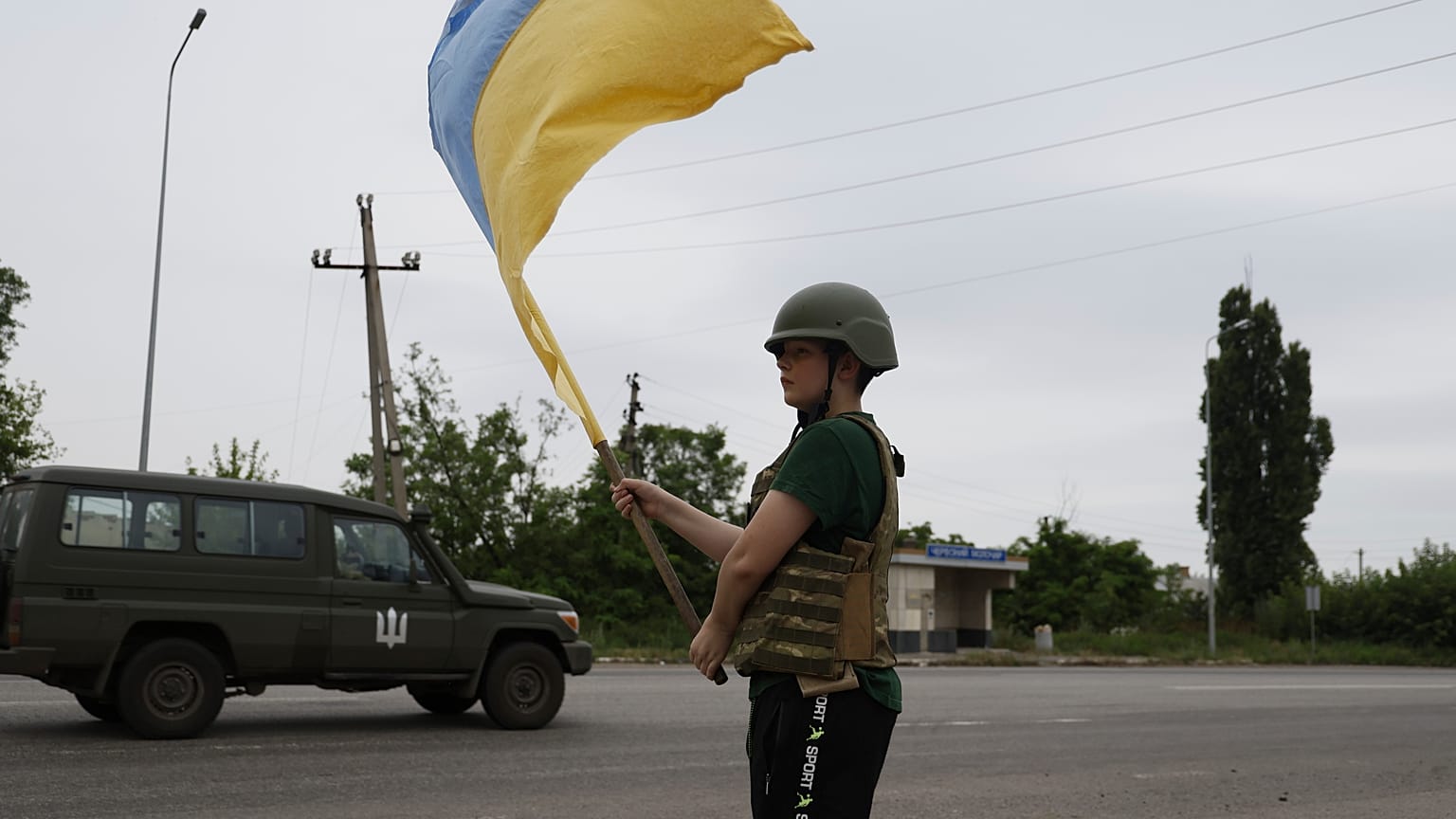 Ребенок встречает украинских военных с флагом на дороге близ Лимана