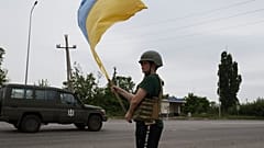Ребенок встречает украинских военных с флагом на дороге близ Лимана