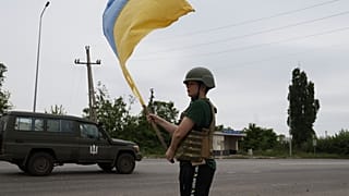 Ребенок встречает украинских военных с флагом на дороге близ Лимана