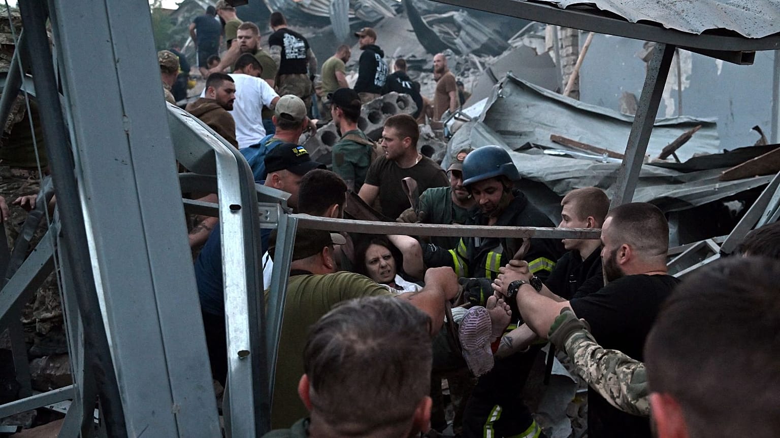 Rescuers and volunteers carry a rescued woman from the rubble after Russian missile strike hit a restaurant and several houses in Kramatorsk