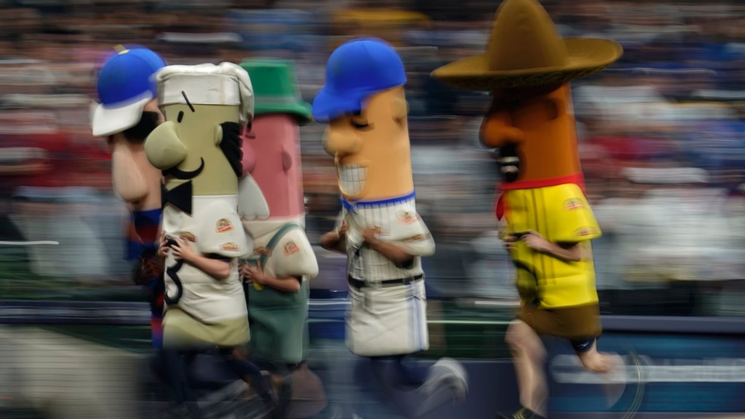 The Racing Sausages run during the sixth inning of a baseball game, 2023.