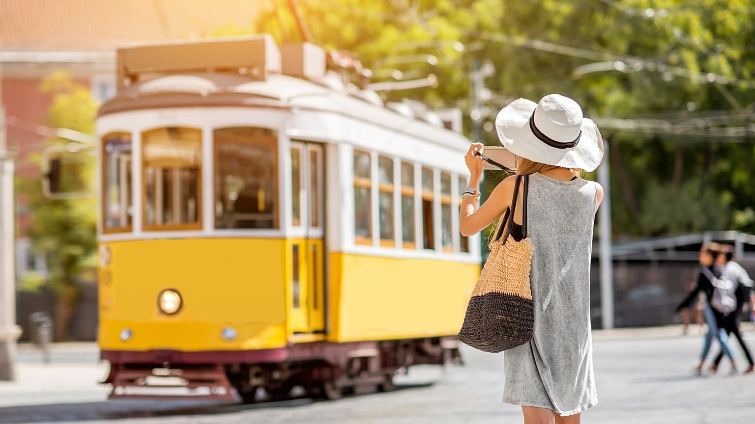 A tourist takes a photo of a tram in Lisbon