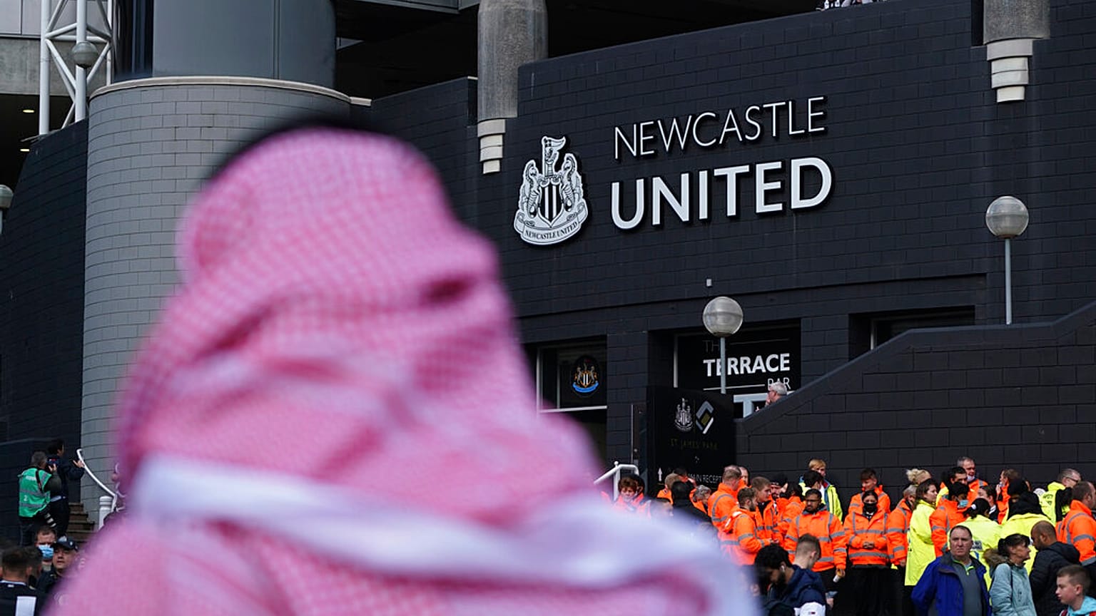 A man with a Saudi Arabian headdress pases by St. James' Park in Newcastle. 