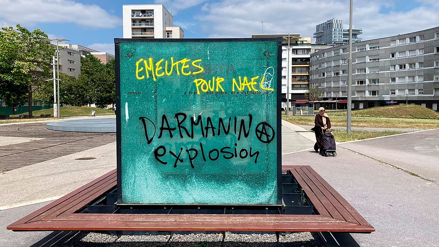 Graffiti reads "Riots for Nahel, Explosion for Darmanin," referring to French Interior Minister Gerald Darmanin, on an urban furniture on July 2 in the Paris suburb Nanterre.